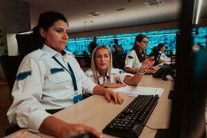 Group of female security operators working in a data system control room Technical Operators Working at workstation with multiple displays, security guards working on multiple monitors in surveillan photo