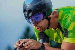 Close up photo of an active triathlete in sportswear and with a protective helmet riding a bicycle. Selective focus