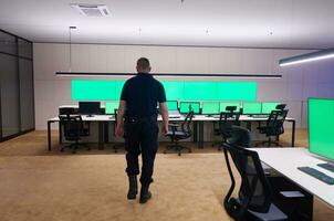 young male security operator walking through data system control room photo