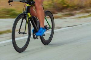 Close up photo of an active triathlete in sportswear and with a protective helmet riding a bicycle. Selective focus