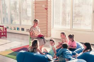 Reading time in elementary school or kindergarten, teacher reading a book to kids in elementary school or kindergaden. Selective focus photo