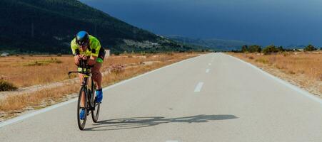 Full length portrait of an active triathlete in sportswear and with a protective helmet riding a bicycle. Selective focus photo