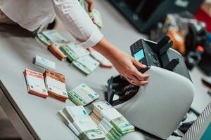 Bank employees using money counting machine while sorting and counting paper banknotes inside bank vault. Large amounts of money in the bank photo