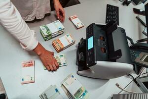 Bank employees using money counting machine while sorting and counting paper banknotes inside bank vault. Large amounts of money in the bank photo