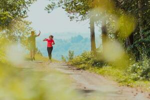 Couple enjoying in a healthy lifestyle while jogging on a country road through the beautiful sunny forest, exercise and fitness concept photo