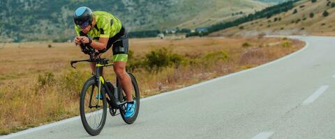 Full length portrait of an active triathlete in sportswear and with a protective helmet riding a bicycle. Selective focus photo