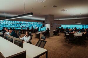 Group of Security data center operators working in a CCTV monitoring room looking on multiple monitors Officers Monitoring Multiple Screens for Suspicious Activities Team working on the System Contr photo