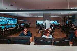 Group of Security data center operators working in a CCTV monitoring room looking on multiple monitors Officers Monitoring Multiple Screens for Suspicious Activities Team working on the System Contr photo