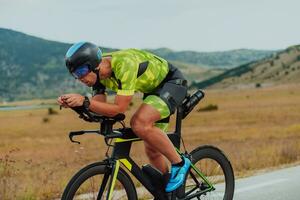 Full length portrait of an active triathlete in sportswear and with a protective helmet riding a bicycle. Selective focus photo