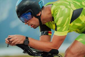 Close up photo of an active triathlete in sportswear and with a protective helmet riding a bicycle. Selective focus