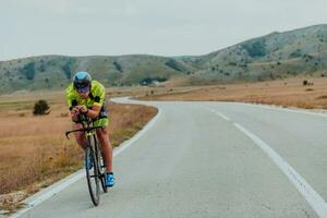 Full length portrait of an active triathlete in sportswear and with a protective helmet riding a bicycle. Selective focus photo