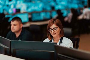 Female security operator working in a data system control room offices Technical Operator Working at workstation with multiple displays, security guard working on multiple monitors photo