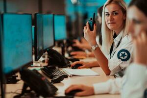 Female security operator holding portable radio in hand while working in a data system control room offices Technical Operator Working at workstation with multiple displays, security guard working on photo