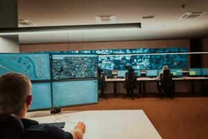 Male security operator working in a data system control room offices Technical Operator Working at workstation with multiple displays, security guard working on multiple monitors Male computer opera photo