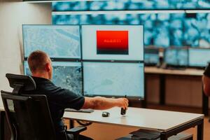 Male security operator working in a data system control room offices Technical Operator Working at workstation with multiple displays, security guard working on multiple monitors Male computer opera photo