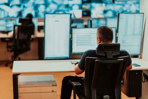 Male security operator working in a data system control room offices Technical Operator Working at workstation with multiple displays, security guard working on multiple monitors Male computer opera photo