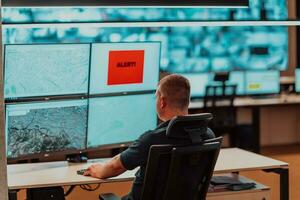 Male security operator working in a data system control room offices Technical Operator Working at workstation with multiple displays, security guard working on multiple monitors Male computer opera photo