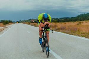 lleno longitud retrato de un activo triatleta en ropa de deporte y con un protector casco montando un bicicleta. selectivo atención foto