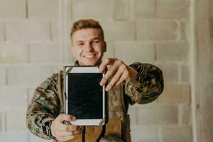 Soldier using tablet computer against old brick wall photo