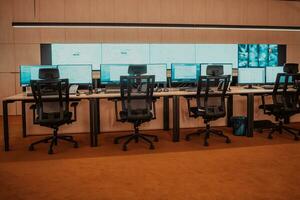 Empty interior of big modern security system control room, workstation with multiple displays, monitoring room with at security data center Empty office, desk, and chairs at a main CCTV security data photo