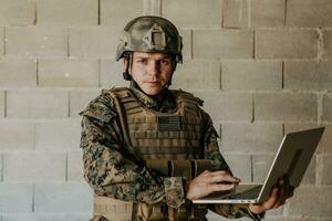 American soldier in military uniform using laptop computer for drone controlling and to stay in contact with friends and family photo