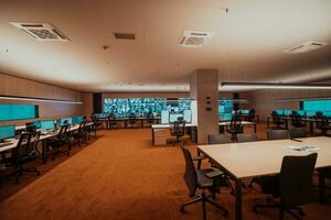 Empty interior of big modern security system control room, workstation with multiple displays, monitoring room with at security data center Empty office, desk, and chairs at a main CCTV security data photo