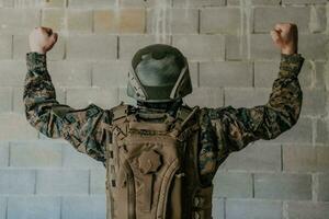 éxito en el guerra campaña. un soldado con elevado manos celebra el exitoso conquista de enemigo territorio foto