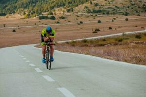 Full length portrait of an active triathlete in sportswear and with a protective helmet riding a bicycle. Selective focus photo