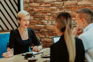 contento gente de negocios sonriente alegremente durante un reunión en un café tienda. grupo de exitoso negocio profesionales trabajando como un equipo en un multicultural lugar de trabajo. foto