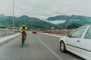 Full length portrait of an active triathlete in sportswear and with a protective helmet riding a bicycle. Selective focus photo