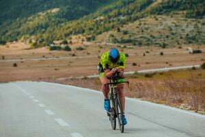 Full length portrait of an active triathlete in sportswear and with a protective helmet riding a bicycle. Selective focus photo