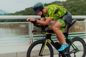 lleno longitud retrato de un activo triatleta en ropa de deporte y con un protector casco montando un bicicleta. selectivo atención foto