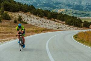 Full length portrait of an active triathlete in sportswear and with a protective helmet riding a bicycle. Selective focus photo