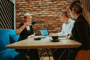 Happy businesspeople smiling cheerfully during a meeting in a coffee shop. Group of successful business professionals working as a team in a multicultural workplace. photo