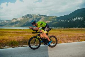 Full length portrait of an active triathlete in sportswear and with a protective helmet riding a bicycle. Selective focus photo