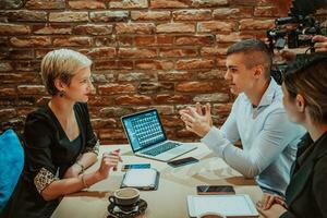 Happy businesspeople smiling cheerfully during a meeting in a coffee shop. Group of successful business professionals working as a team in a multicultural workplace. photo