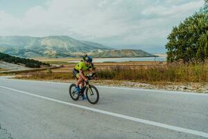 Full length portrait of an active triathlete in sportswear and with a protective helmet riding a bicycle. Selective focus photo