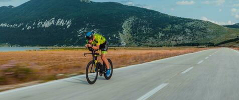 Full length portrait of an active triathlete in sportswear and with a protective helmet riding a bicycle. Selective focus photo