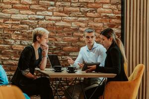 Happy businesspeople smiling cheerfully during a meeting in a coffee shop. Group of successful business professionals working as a team in a multicultural workplace. photo