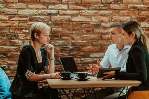 Happy businesspeople smiling cheerfully during a meeting in a coffee shop. Group of successful business professionals working as a team in a multicultural workplace. photo