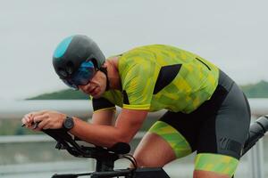 Close up photo of an active triathlete in sportswear and with a protective helmet riding a bicycle. Selective focus