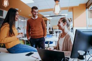 Group of multi-ethnic colleagues working on desktop computers, laptop and sharing their ideas in a modern office space.Young influencers work on online marketing projects. photo