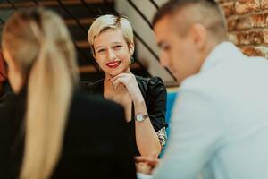 Happy businesspeople smiling cheerfully during a meeting in a coffee shop. Group of successful business professionals working as a team in a multicultural workplace. photo
