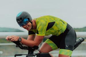 Close up photo of an active triathlete in sportswear and with a protective helmet riding a bicycle. Selective focus