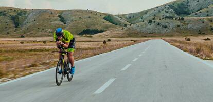 Full length portrait of an active triathlete in sportswear and with a protective helmet riding a bicycle. Selective focus photo