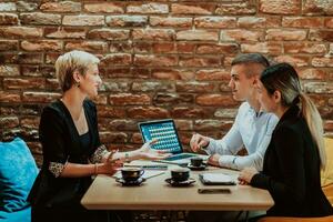 Happy businesspeople smiling cheerfully during a meeting in a coffee shop. Group of successful business professionals working as a team in a multicultural workplace. photo