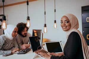 Group of multi-ethnic colleagues working on desktop computers, laptop and sharing their ideas in a modern office space.Young influencers work on online marketing projects. photo