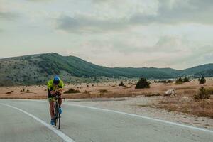 Full length portrait of an active triathlete in sportswear and with a protective helmet riding a bicycle. Selective focus photo