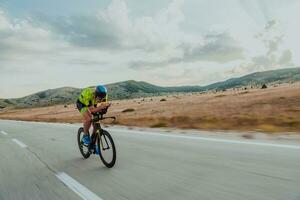 Full length portrait of an active triathlete in sportswear and with a protective helmet riding a bicycle. Selective focus photo