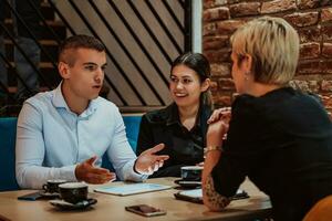 Happy businesspeople smiling cheerfully during a meeting in a coffee shop. Group of successful business professionals working as a team in a multicultural workplace. photo